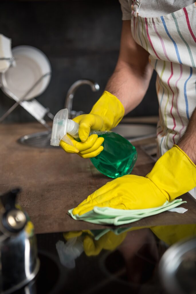 cropped image of man cleaning kitchen with spray bottle and rag